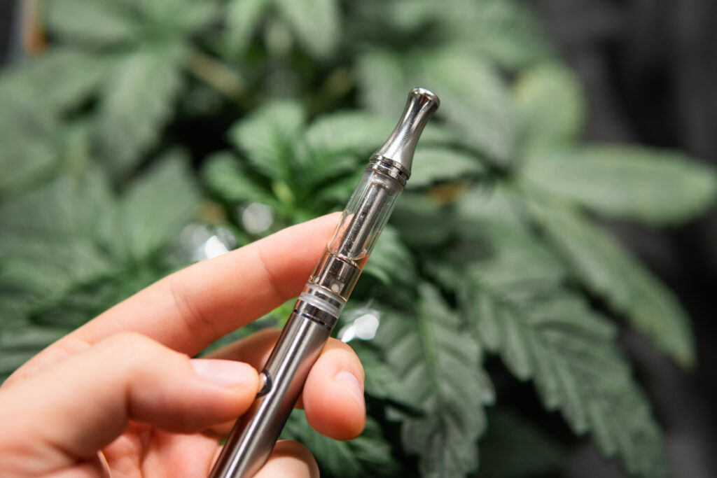 a hand holding metal dab pen